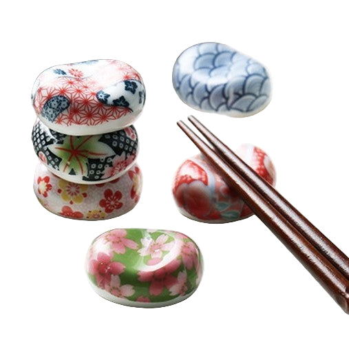 A set of multicolored, pebble-shaped Japanese ceramic chopstick rests with traditional Japanese patterns displayed alongside a pair of chopsticks.