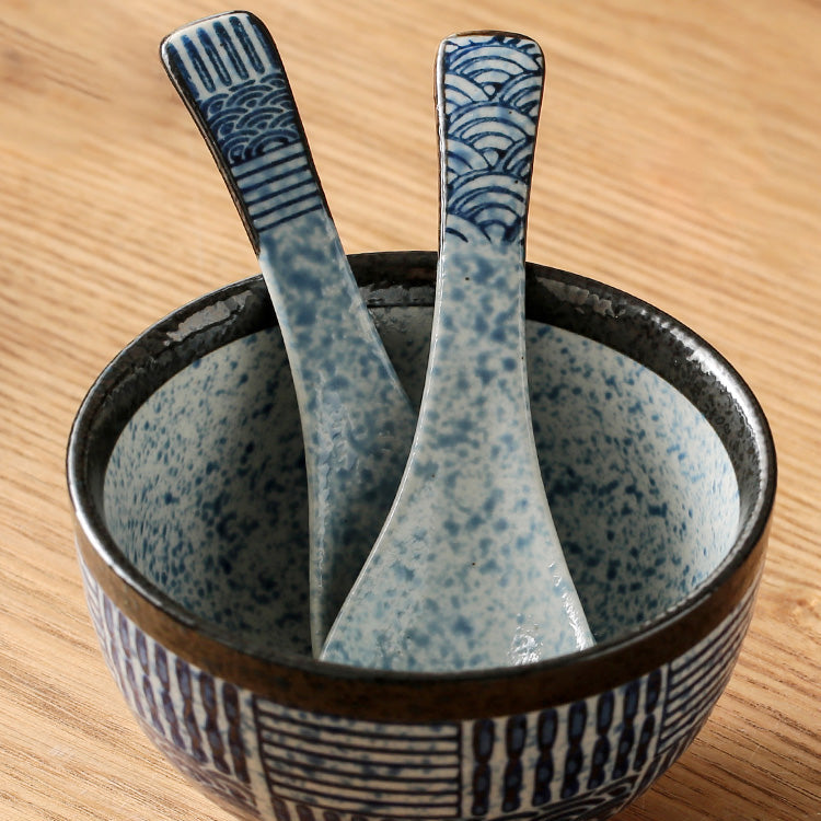 Ceramic bowl with speckled design and matching spoons on a wooden surface