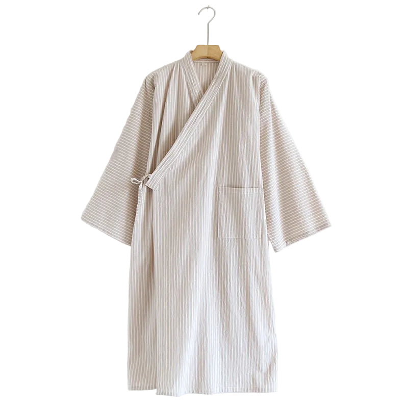 A beige and white vertically striped cotton robe with a wrap-style collar and tie belt, hanging on a wooden hanger against a plain white wall.