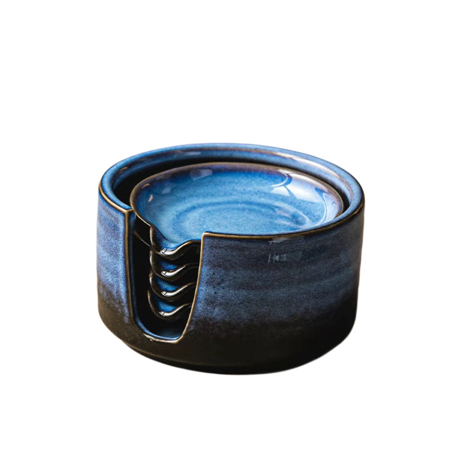 A ceramic ashtray with a glossy blue and black glaze, featuring a slotted design on the front side, shown against a plain white background.