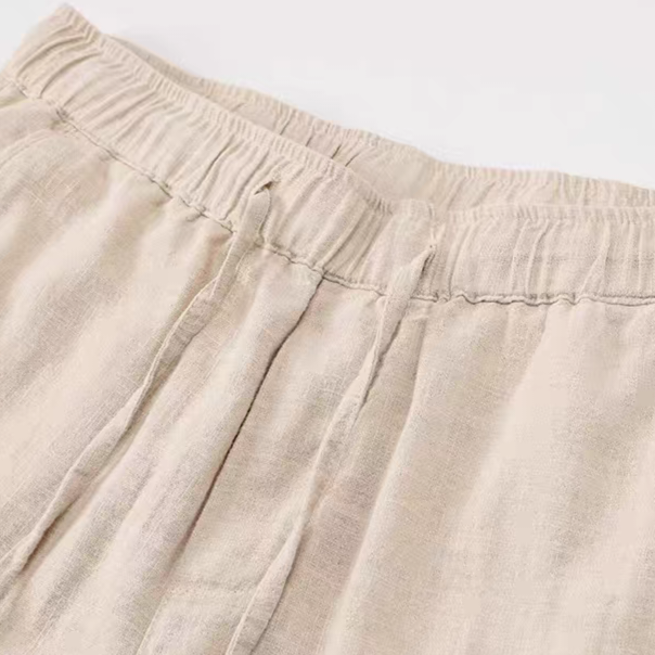 Close-up of a light beige linen garment, showing the elastic waistband and textured fabric.