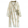 A long-sleeve wrap-style dress or robe in a warm off-white/cream cotton gauze fabric, decorated with a delicate floral print in sage green, soft orange, and light blue. It features a wrap-around V-neckline with a matching sage green tie belt at the waist.