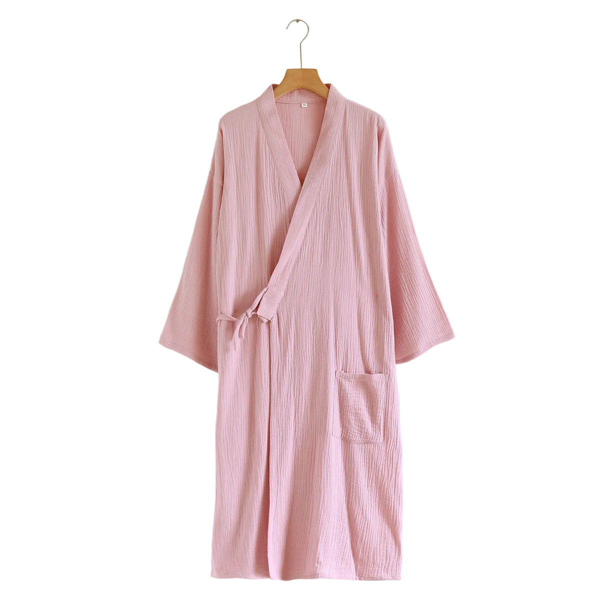 A light pink crinkle-textured cotton robe with a wrap-style collar and tie belt, hanging on a wooden hanger against a plain white wall.