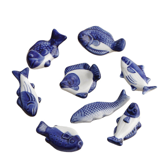 Set of blue and white ceramic fish figurines on a textured surface with text above.