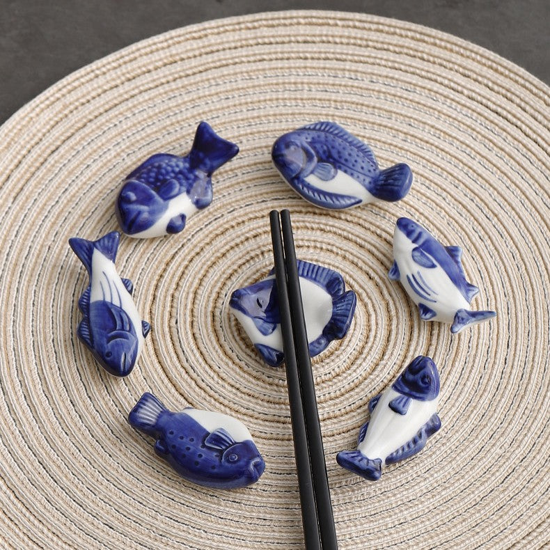 Blue and white fish-shaped ceramic items arranged on a woven mat with black chopsticks.