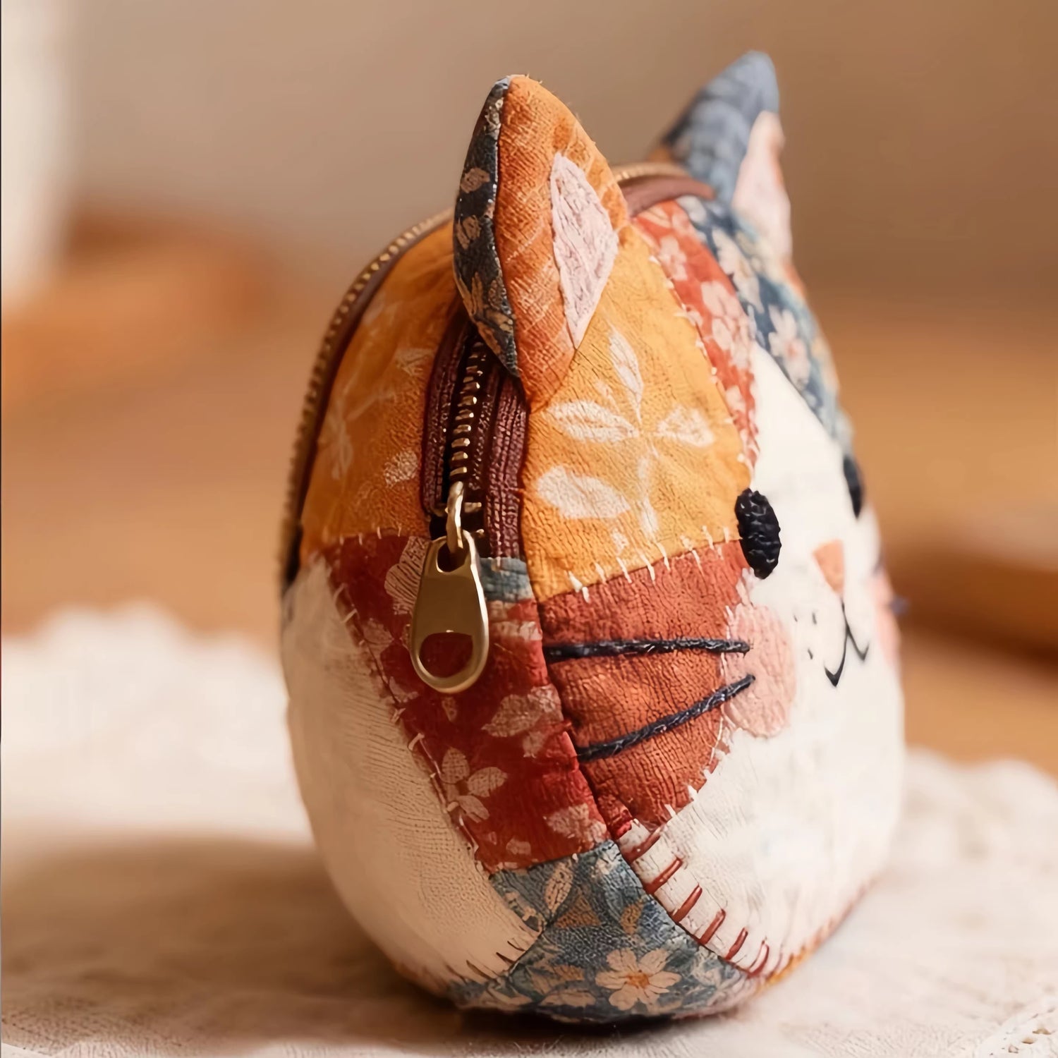 Patchwork cat-shaped coin purse with floral patterns on a soft surface.