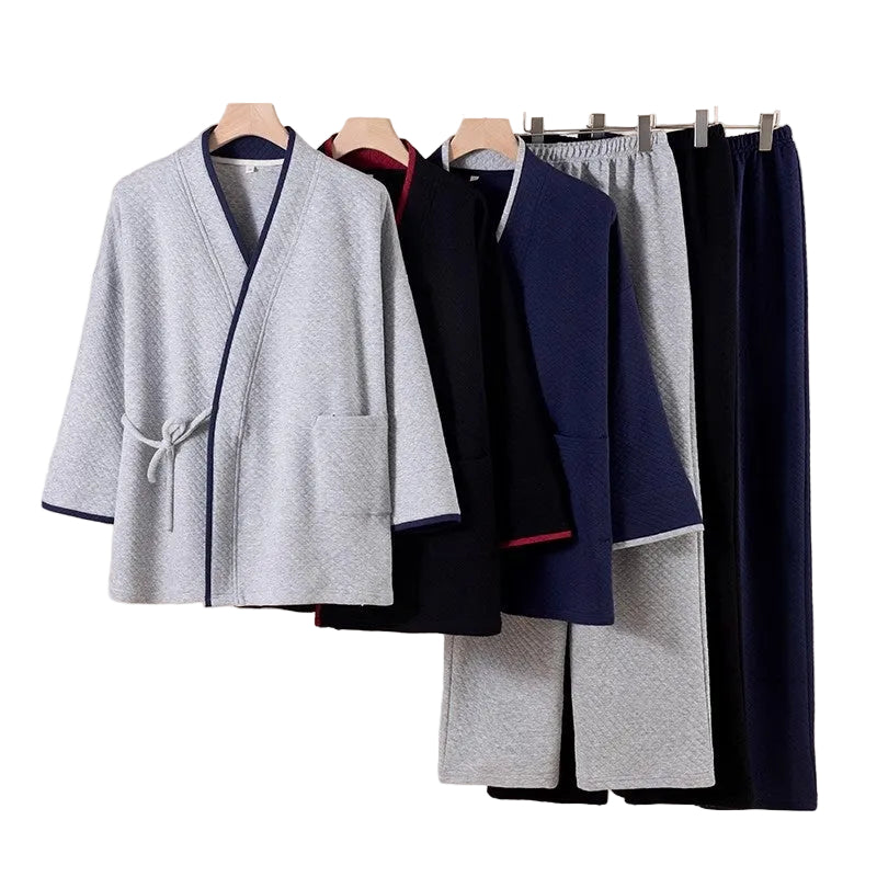 Set of gray and navy robes on hangers against a beige wall.